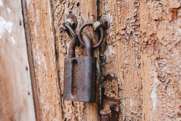 istock Old weathered grunge rusty locked padlock old wooden board door 655777192