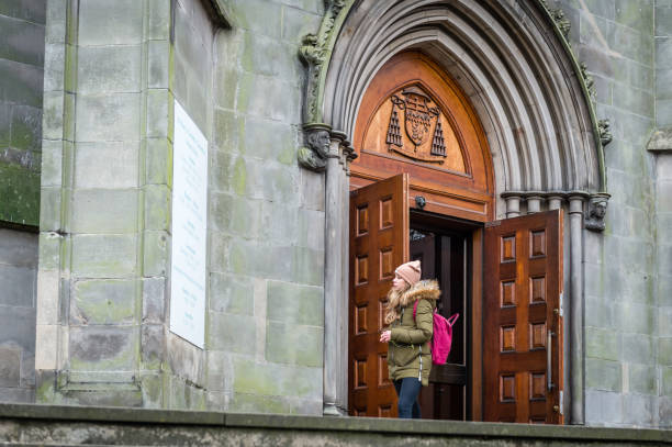 Edinburgh, UK - October 27, 2015: Motion blur as a couple walk past an alleyway leading onto the Grassmarket, in Edinburgh's historic Old Town, with people and traffic on Victoria Street in the background.