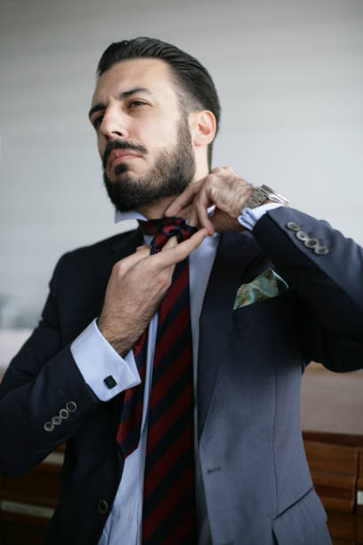 istock Young business man tying a tie in his office 655798738