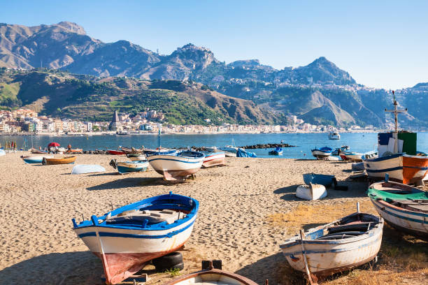 boats on urban beach in giardini naxos town travel to Italy - boats on urban beach in giardini naxos town in Sicily in summer morning giardini naxos stock pictures, royalty-free photos & images