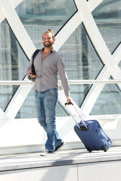 istock Smiling travel man walking with suitcase and smart phone 655811424