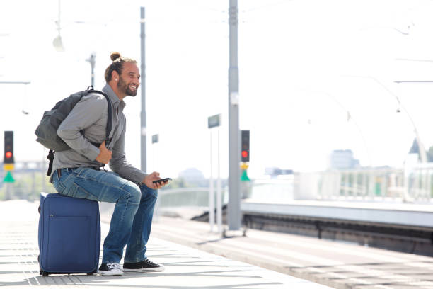istock Cool man waiting at train station with mobile phone and bags 655811450