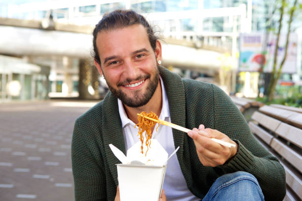 istock Happy man eating take out food with chopsticks 655813684