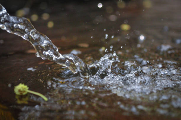 Abstract background of water spraying into a pond from a hose in golden evening light.