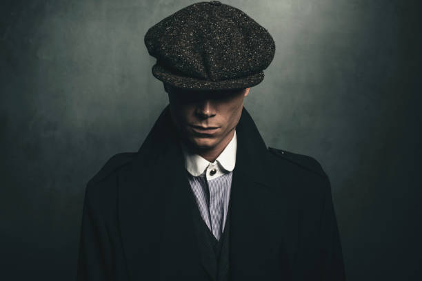Mysterious portrait of retro 1920s english gangster with flat cap. Mysterious portrait of retro 1920s english gangster with flat cap. flat cap stock pictures, royalty-free photos & images