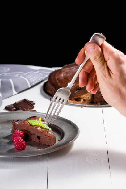 istock Man hand try a piece of cake chocolate brownie. 655824648
