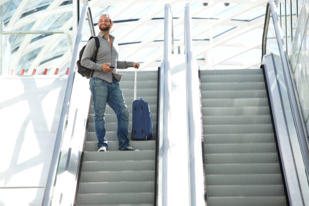 istock Travel man standing on escalator with bags 655839814