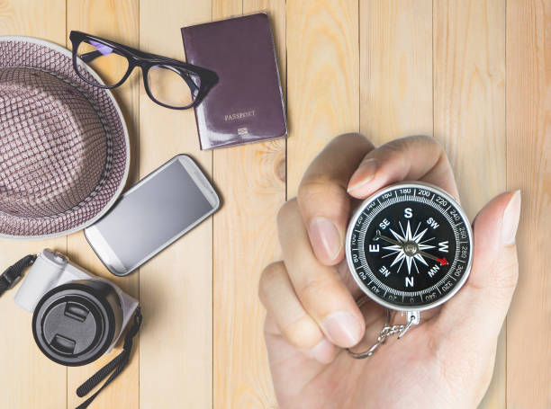 istock Explorer holding compass with travel accessories in background 655840724