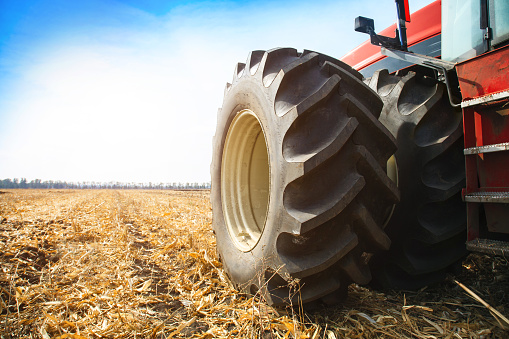 Modern red tractor in the field close-up on a bright sunny day