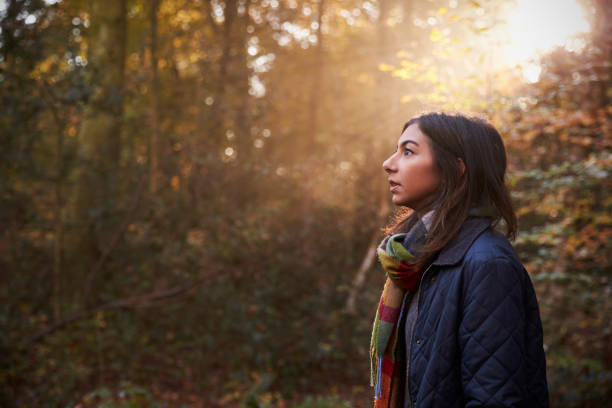 istock Woman Walks In Autumn Forest With Sun Shining Through Trees 655867540