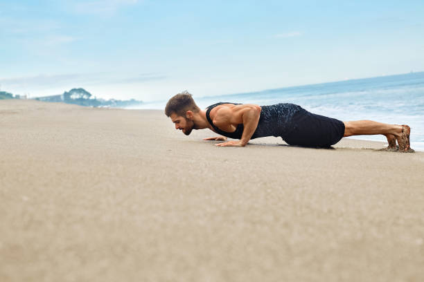 istock Fitness Man Exercising, Doing Push Ups Exercise On Beach. Sports 655867726