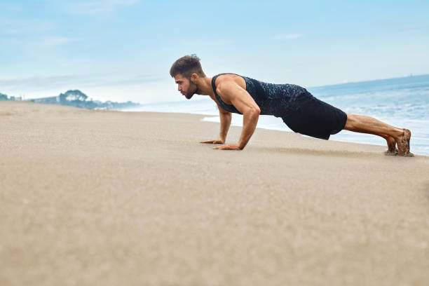 istock Fitness Man Exercising, Doing Push Ups Exercise On Beach. Sports 655874456