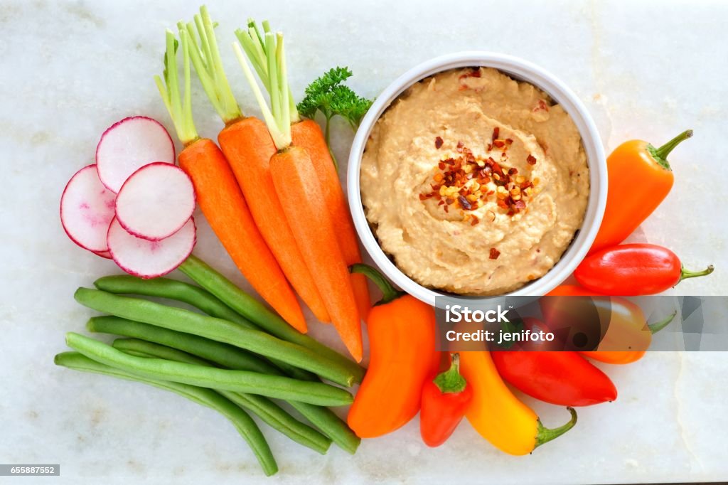 Hummus with fresh vegetables, above view on white marble Hummus dip with a variety of fresh vegetables, above view on a white marble background Hummus - Food Stock Photo