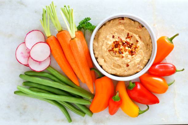 Hummus with fresh vegetables, above view on white marble Hummus dip with a variety of fresh vegetables, above view on a white marble background hot mix plant stock pictures, royalty-free photos & images