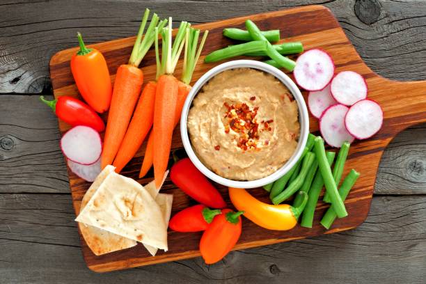 istock Hummus dip with a platter of vegetables, over wood 655887700