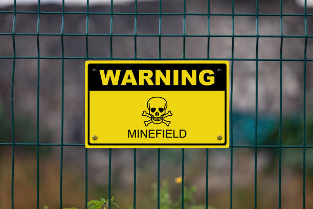 Warning - Minefield Black and yellow warning sign with a skull and bones with written bellow it “Minefield”. land mine stock pictures, royalty-free photos & images