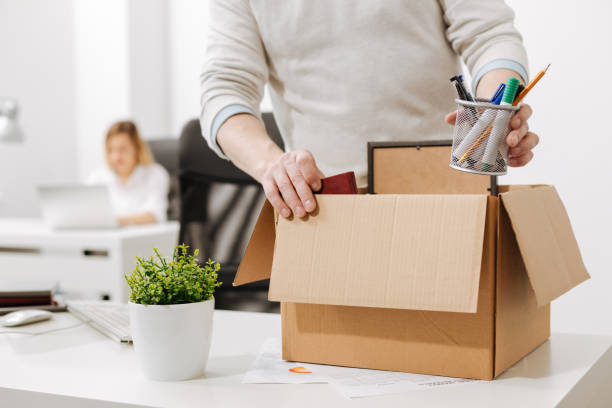Upset office manager packing the box and leaving the office Taking a gap. Concentrated involved melancholy employee standing and packing the box with his belongings while leaving the company and expressing sadness quitting a job stock pictures, royalty-free photos & images