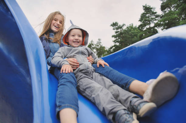 istock Smiling girl and boy having fun on children's slide 655916936