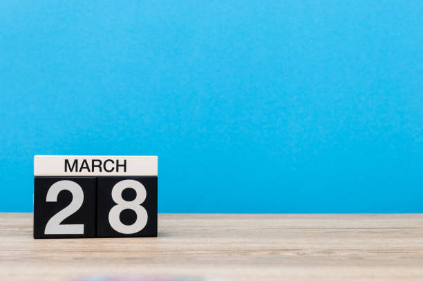 March 28th. Day 28 of month, calendar on table with blue background. Spring time, empty space for text