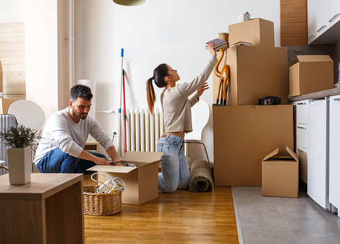 Young couple unpacking cardboard boxes at new home.Moving house.