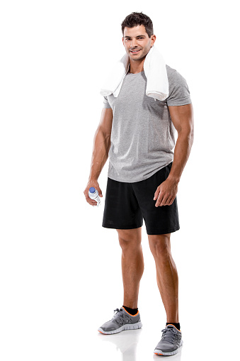 Portrait of a athletic man after doing exercises and holding a bottle of water, isolated over a white background