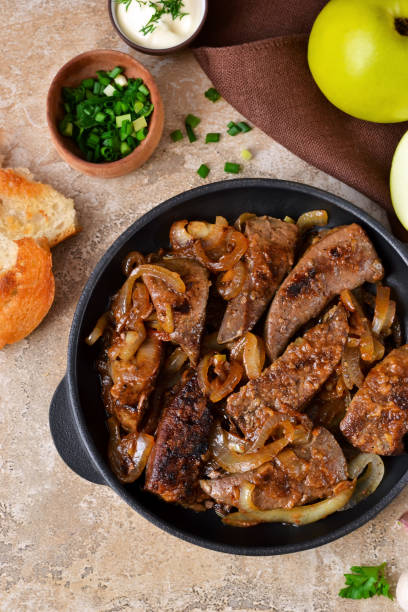 istock Fried liver with onions and apples on a concrete background 655931368