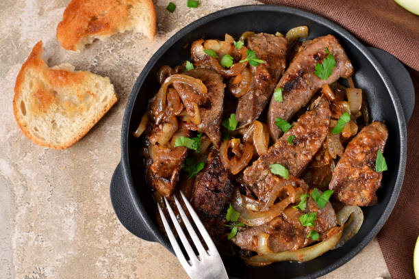 Fried liver with onions and apples on a concrete background stock photo