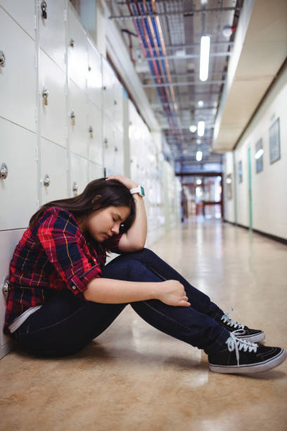 istock Depressed female student sitting in locker room 655937140