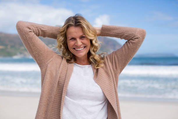 istock Mature woman with hands behind head standing on the beach 655941700