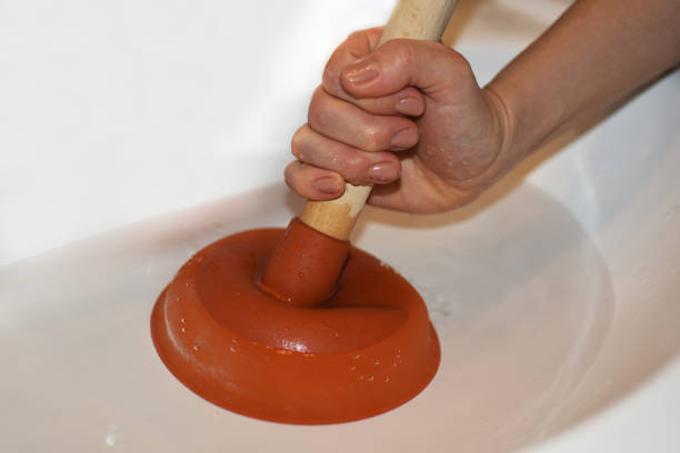 mujer con un émbolo tratando de eliminar sumideros obstruidos. - plunger fotografías e imágenes de stock