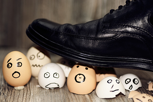 Abstract composition of business leadership. Broken eggs under mans shoes.