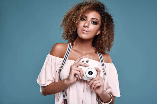 elegant black woman model with curly hair and camera - photographer enjoyment elegance old fashioned imagens e fotografias de stock