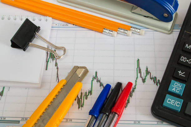 istock Calculator, colored pen pencils, stapler and clerical knife on the financial chart 655973206