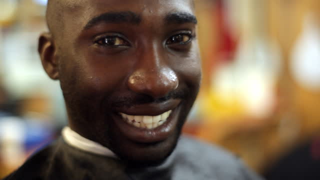 A barbershop customer smiles after getting his head shaved.