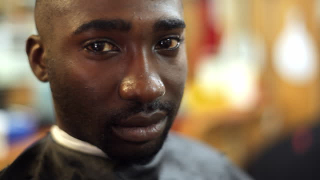 A barbershop customer looks seriously at the camera.