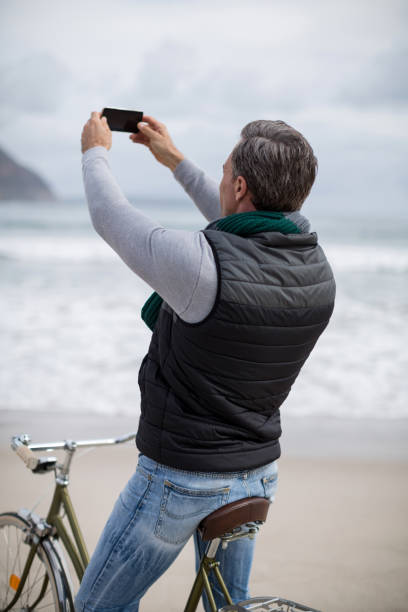 istock Mature man photographing scenery using cell phone 655989240