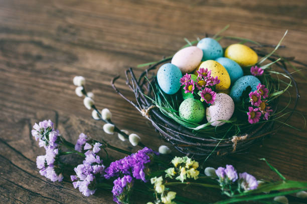 istock Easter background. Bright colorful eggs in nest with spring flowers over wooden dark background. Selective focus with copy space 655989328