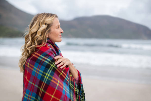 istock Mature woman wrapped in shawl on the beach 655999072