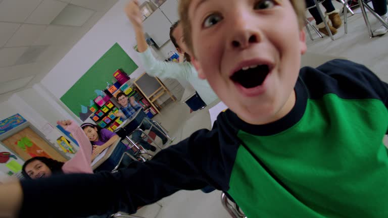 Elementary students yell and cheer at their desks during class.