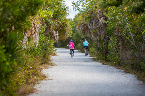 People Bicycling down a gravel path in Ding Darling National Wildlife Refuge on Sanibel Island, Florida, USA