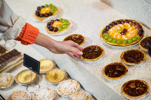 Woman selecting tart from display in supermarket