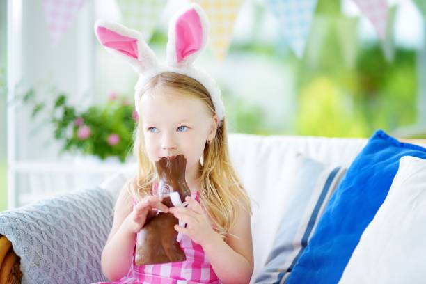 istock Cute little girl wearing bunny ears eating chocolate Easter rabbit 656025974