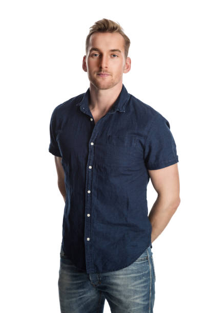 Blonde attractive man with a smile Handsome blonde man in blue shirt and jeans standing against a white background smiling. short sleeved stock pictures, royalty-free photos & images