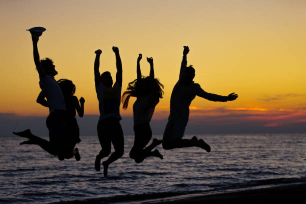 istock silhouette of friends jumping on beach during sunset time 656028718
