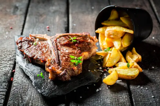 Photo of Fresh tbone steak and chips with herbs and salt