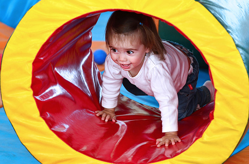 A baby girl has fun and plays in an indoor playground.