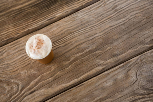 Close-up of coffee in disposable cup on wooden table