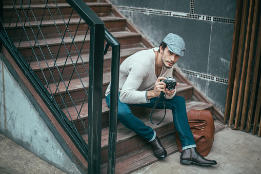 One man,sitting on the steps, holding a camera,