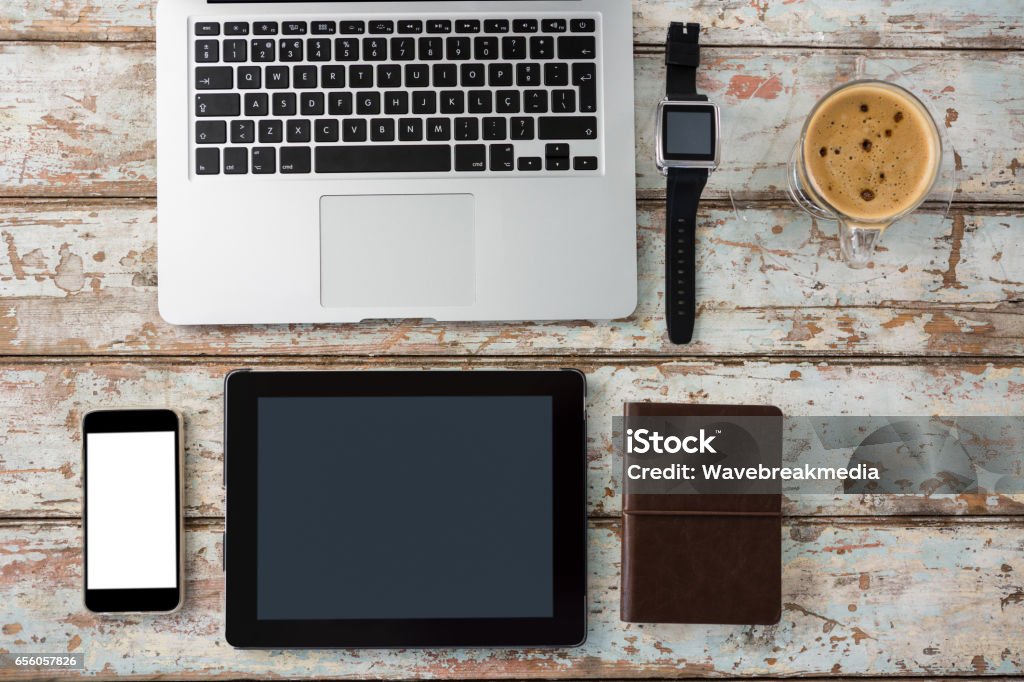 Laptop, smartwatch, smartphone and digital tablet with cup of coffee Laptop, smartwatch, smartphone and digital tablet with cup of coffee on wooden table Brown Stock Photo