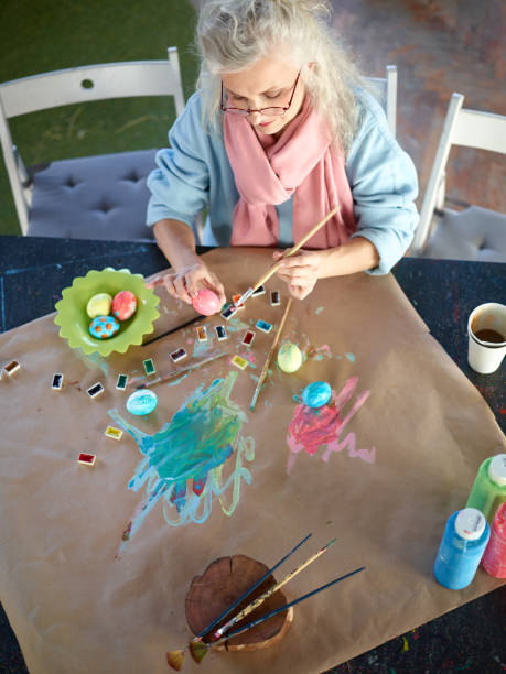 istock Aged woman painting eggs 656073124